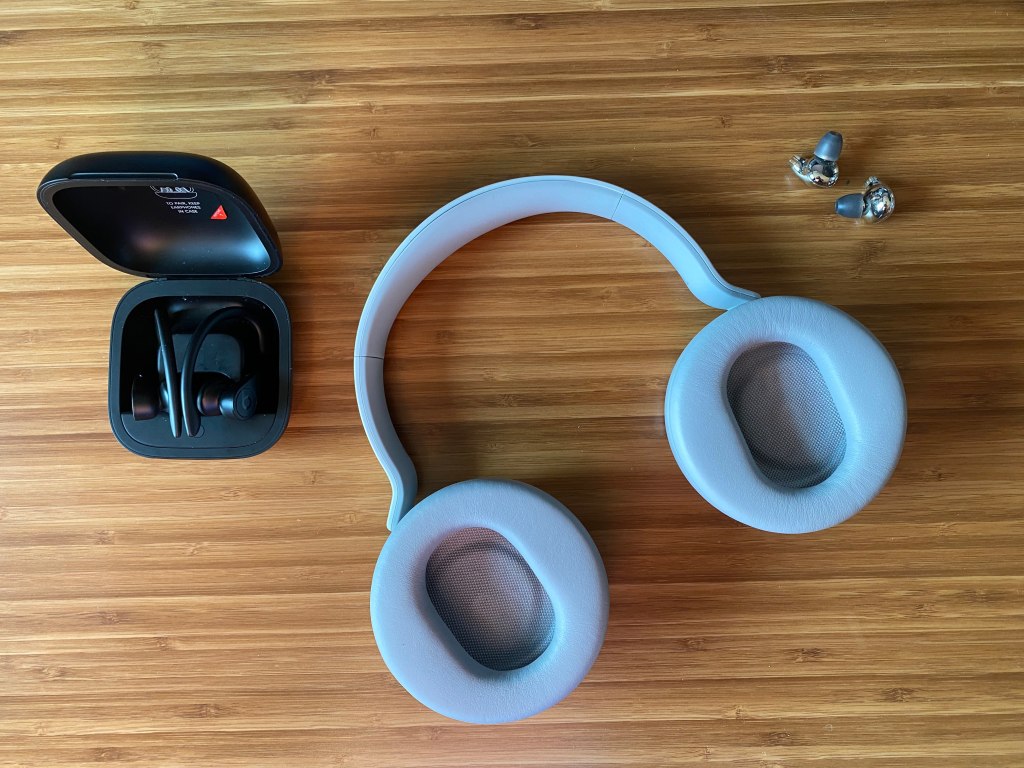 Top view of Bluetooth headphones and earbuds on a desk.