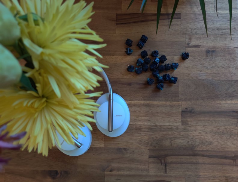 Keyboard switches on a desk next to flowers and headphones.