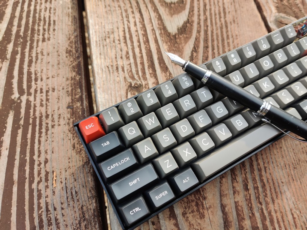Mechanical keyboard with a fountain pen on top.